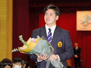 母校の神港橘高で講演し、花束を受け取った金丸夢斗投手＝神戸市兵庫区