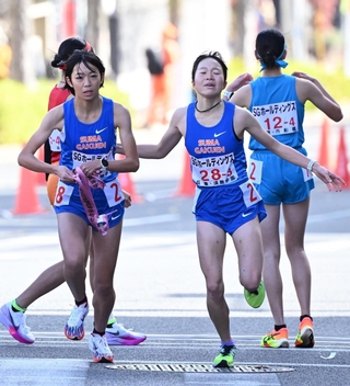 女子・須磨学園の３区池野絵莉（右）からたすきを受け取る４区東はる（撮影・大田将之）