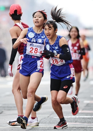 ８区の朝日小都子（左）からアンカーの田中希実にたすきが渡る＝１２日午後、京都市（撮影・長嶺麻子）