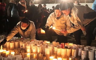 発生時刻を前に、東遊園地で灯籠に火をともしたラグビー神戸の選手ら＝神戸市中央区