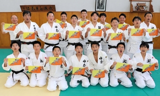 ブータン国旗を手に笑顔を見せる甲南大や関学大、神戸灘中、甲南中・高の柔道部員ら＝神戸市東灘区