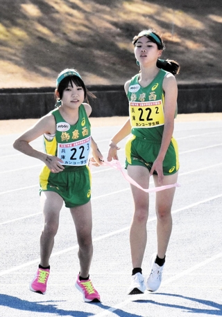 女子・飾磨西の３区有井桃（左）が２区田上奏からたすきを受け取る