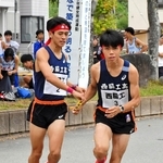 地区予選会で男子・西脇工の中道琉惺（左）からたすきを受け取る新妻昂己＝西脇市総合市民センター