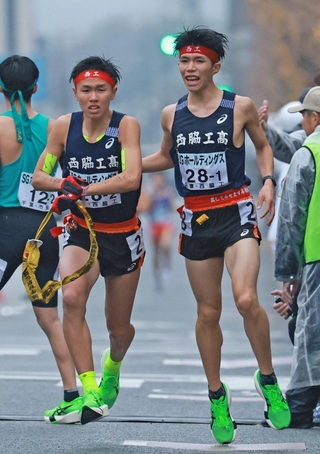 男子・西脇工の１区新妻遼己（右）からたすきを受ける２区岩崎奏（撮影・鈴木雅之）