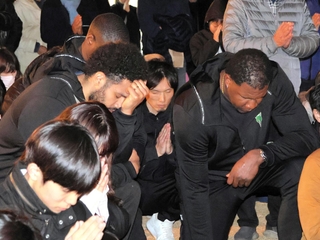 午後５時４６分に手を合わせる神戸ストークスの谷直樹（中央奥）ら＝神戸市中央区、東遊園地