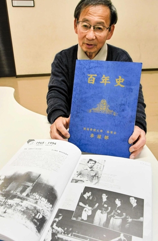 関学大卓球部の百年史を手にする鯛中昌洋さん＝神戸市長田区
