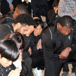 午後５時４６分に手を合わせるＢ２神戸の谷直樹（中央奥）ら＝神戸市中央区、東遊園地