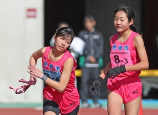 尼崎市３区の関口花奈（右）からたすきを受け取る４区の久能皐央＝三木市志染町三津田、三木総合防災公園陸上競技場（撮影・丸山桃奈）