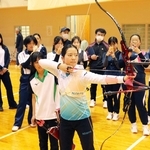 上原瑠果（手前）の試射を間近で見学する中高生ら＝神戸市西区、兵庫県立障害者スポーツ交流館