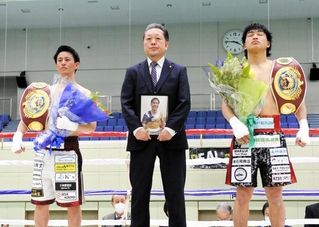 穴口一輝さんの遺影とともに引退のテンカウントゴングを聞く大橋哲朗（右）と小林豪己（左）。中央は真正ジムの山下正人会長＝８日、神戸市立中央体育館