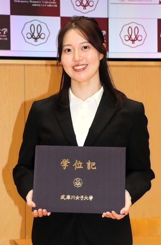 大学院を修了し、学位記を手に笑顔を見せる藤木日菜＝西宮市、武庫川女大