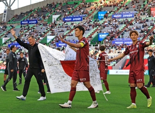 ＡＣＬＥ壮行式でサポーターのメッセージが書き込まれた日の丸を持ち、あいさつするスキッベ監督（左）ら（撮影・丸山桃奈）