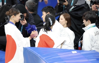 ミラノ・コルティナ冬季五輪で女子銀メダルを獲得し、三浦璃来（右）と木原龍一（中央奥）らからねぎらわれる坂本花織（左）＝２月、ミラノ