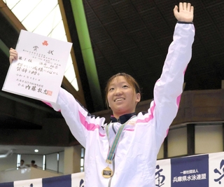 女子１００メートル自由形を大会新記録で制し、表彰台で笑顔を見せる須磨学園の酒井柚奈