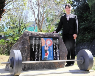 母校に設置された記念碑とともに笑顔を見せる八木かなえさん＝須磨友が丘高