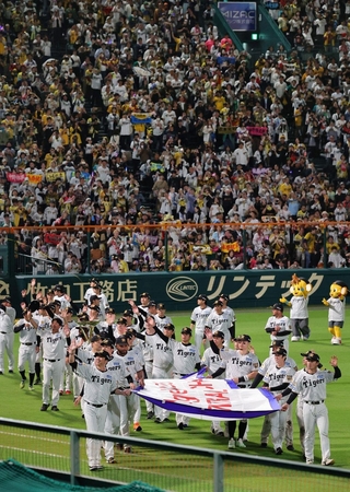 リーグ優勝のペナントを持ってグラウンドを一周する阪神・藤川球児監督や選手たち＝６日夜、西宮市の甲子園球場（撮影・笠原次郎）