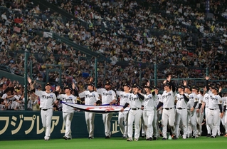 リーグ優勝のペナントを手にグラウンドを一周する阪神・藤川球児監督（左）と選手たち＝６日夜、西宮市の甲子園球場（撮影・吉田敦史）