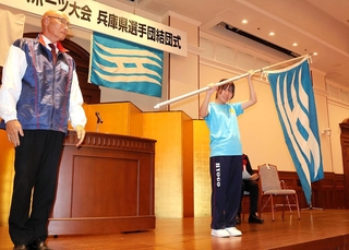 兵庫県選手団の増田和茂団長（左）から県旗を受け取った旗手の岩佐桜星＝神戸市中央区、県公館