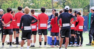 アイナックフットボールクラブ常務取締役の大塚健護氏（中央奥）から新スタジアム計画の説明を受ける選手ら＝神戸市東灘区、神戸レディースフットボールセンター
