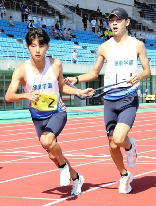 地区予選会でたすきをつなぐ男子・須磨学園の大柿司（右）と東海成＝三木総合防災公園陸上競技場
