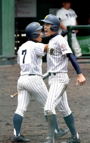 ２０１８年５月、春季近畿高校野球大会の大阪桐蔭戦で、本塁に生還し、次打者とタッチを交わす明石商の植本亮太さん（右）＝兵庫県明石市の明石トーカロ球場