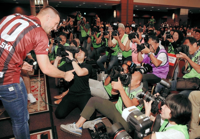 入団会見でカメラマンにケーキを振舞うルーカス・ポドルスキ選手＝神戸市中央区、神戸ポートピアホテル