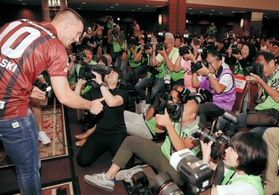 入団会見でカメラマンにケーキを振舞うルーカス・ポドルスキ選手＝神戸市中央区、神戸ポートピアホテル