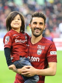 自身のＪ初ゴールでチームを勝利に導き、子どもを抱いて客席に笑顔を見せる神戸のビジャ＝ノエビアスタジアム神戸（撮影・吉田敦史）