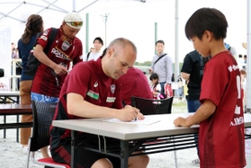 ファンの子どもにサインを書く神戸のイニエスタ（中央）＝神戸市西区、いぶきの森球技場