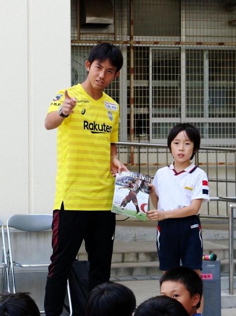 男児に撮影用のカメラ方向を指さすＪ１神戸のＧＫ飯倉大樹＝神戸市兵庫区大開通４、兵庫大開小学校