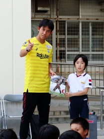 男児に撮影用のカメラ方向を指さすＪ１神戸のＧＫ飯倉大樹＝神戸市兵庫区大開通４、兵庫大開小学校