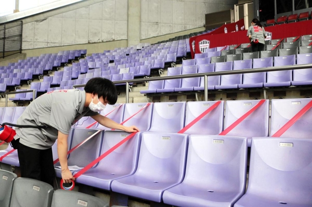感染防止対策のため、スタジアムの空席をテープで封鎖するスタッフら＝神戸市兵庫区、ノエビアスタジアム神戸
