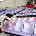 感染防止対策のため、スタジアムの空席をテープで封鎖するスタッフら＝神戸市兵庫区、ノエビアスタジアム神戸