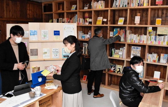 「だいかい文庫」をオープンした守本陽一さん（左端）。「一箱本棚オーナー」が選んだ多様な本を楽しめる＝豊岡市中央町