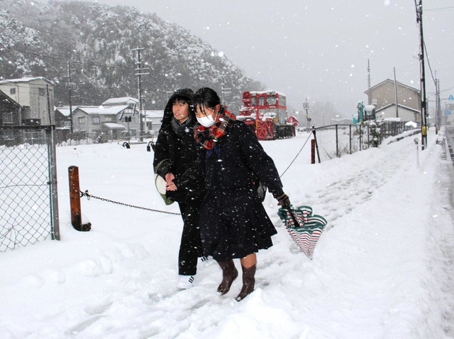 雪が積もった道を下校する高校生＝香美町香住区香住