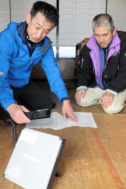 町職員から衛星電話の使い方について説明を受ける孤立集落の住民＝新温泉町高山
