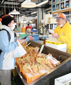 海産物直売所で「地域共通クーポン」を使って松葉ガニを購入する旅行客＝香美町香住区香住