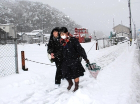 雪が積もった道を下校する高校生＝香美町香住区香住