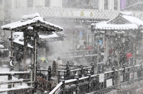 大雪の中、湯村温泉の人気スポット「荒湯」を観光する旅行客＝３１日午前３５分、新温泉町湯、湯村温泉