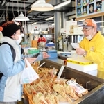 海産物直売所で「地域共通クーポン」を使って松葉ガニを購入する旅行客＝香美町香住区香住