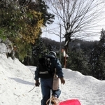 かんじきを履いて雪道を進み、そりに積んだ発電機を運ぶ町職員＝新温泉町高山