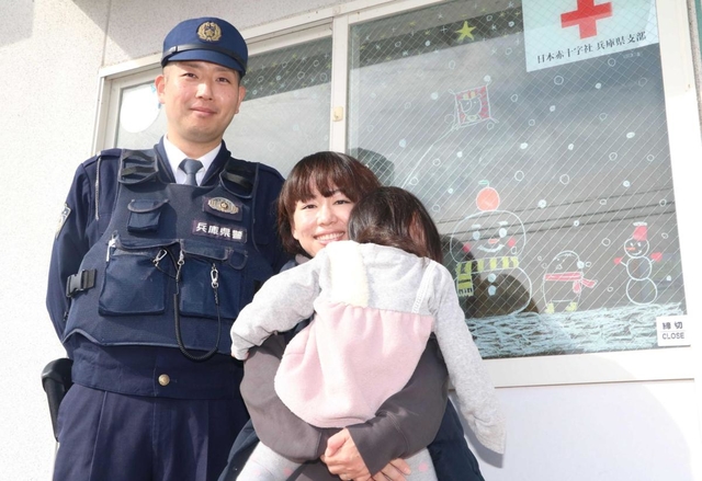 青倉駐在所勤務員の安達弘さん（左）と妻の奈津美さん。駐在所入り口のガラスにもかわいらしい絵が描かれている＝朝来市物部