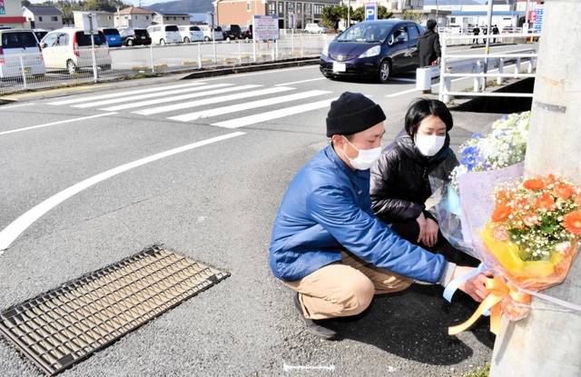 事故のあった交差点で花を供える和田小百合さんと哲治さん＝豊岡市中陰