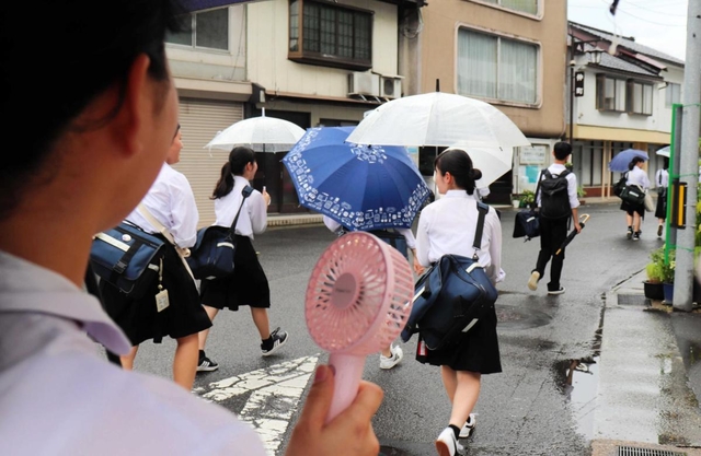 夏場は「手持ち扇風機」も活用して歩く＝養父市八鹿町八鹿、２０２０年７月７日