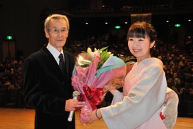 主演映画「太秦ライムライト」の上映会で地元の関係者から花束を受ける福本清三さん（左）＝２０１４年１１月、香美町香住区香住（同町提供）