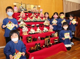 原證さんが寄贈した七段飾りと園児たち＝長井幼稚園