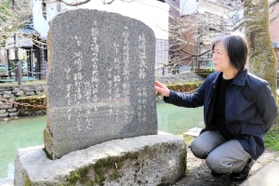 野口雨情の「城崎温泉節」が刻まれた碑を紹介する松井敬代さん＝豊岡市城崎町湯島