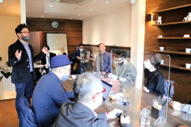 かばんメーカー、コニーの西田正樹社長（左）から話を聞く参加者たち＝豊岡市城崎町湯島