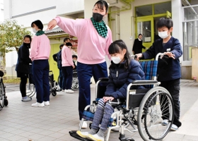 児童に車いす利用者への介助方法を教える高校生ら＝日高高