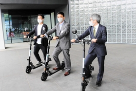 共同会見で電動キックボードをお披露目する各団体の代表者たち＝豊岡市山王町